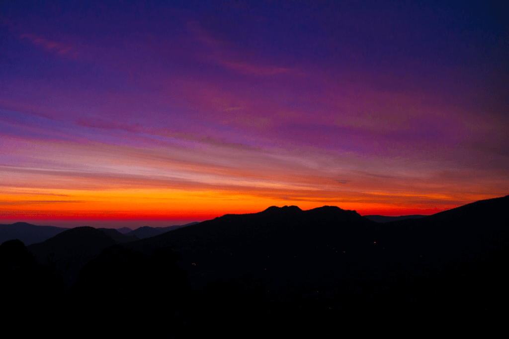 Purple and orange sky over dark hills at sunset